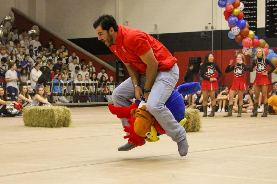 Football Coach Riley Donovan competes in the students versus teachers pep rally game. The game was to go over a stack of hay, turn around an obstacle, and go back to your team while bouncing on the chicken.