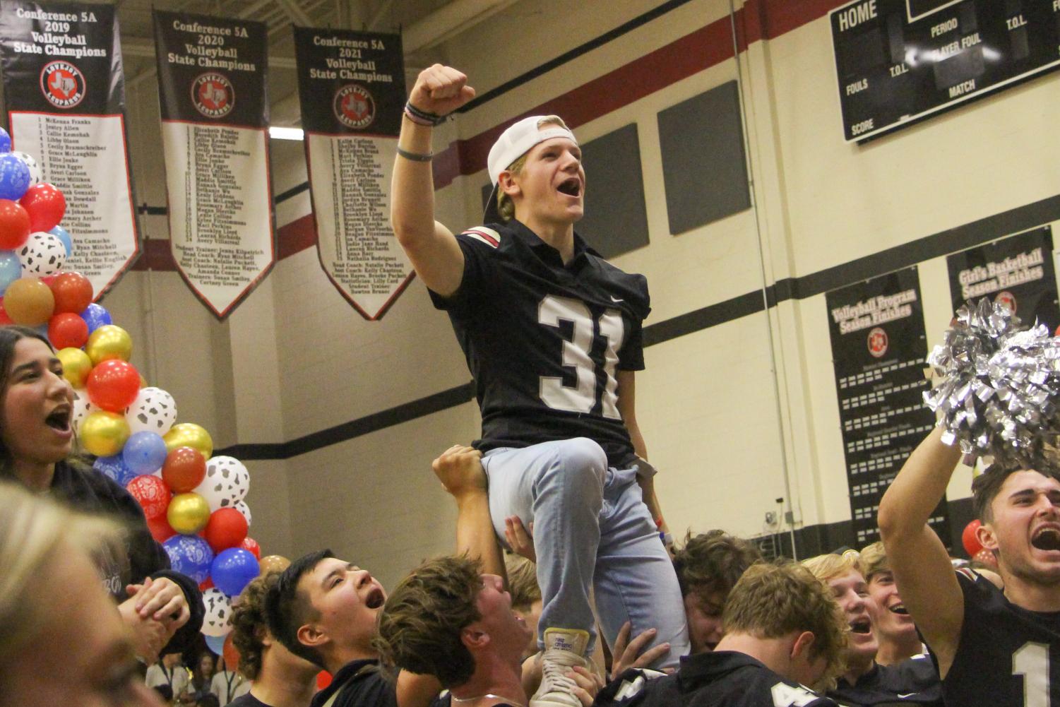 Senior Caden Carlock gets lifted up during the battle cry. Carlock is the kicker for the football team.