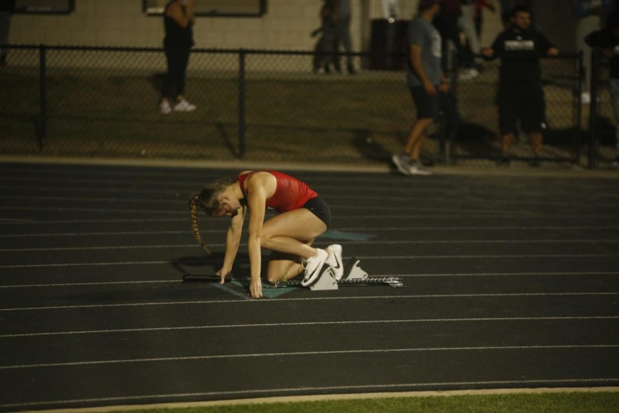 Junior Cambry Patrick gets into the blocks to start to varsity girls 4x4. The relay got 1st with a time of 3:58.74.