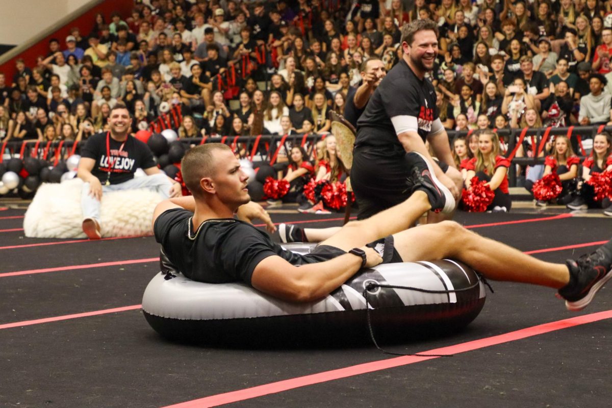 Football coach and teacher John Fee sits in the tube chair after taking it from Principal Travis Zambiasi. Musical chairs is an annual homecoming pep rally event.