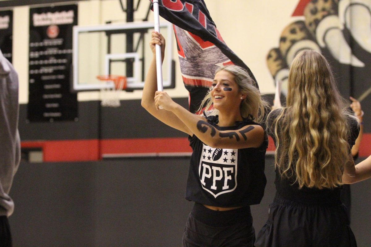 Senior Isabella Camacho runs into the gym holding a flag. The flag says Lojo Jungle. 