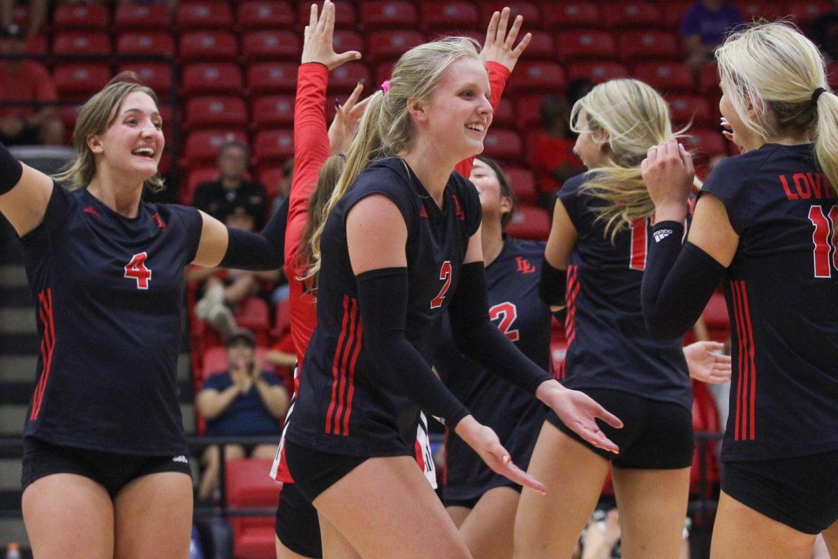 Junior no. 2 Shelby Burriss high fives a teammate after they make a block in the second set of the game.  The team won the set 25-11.