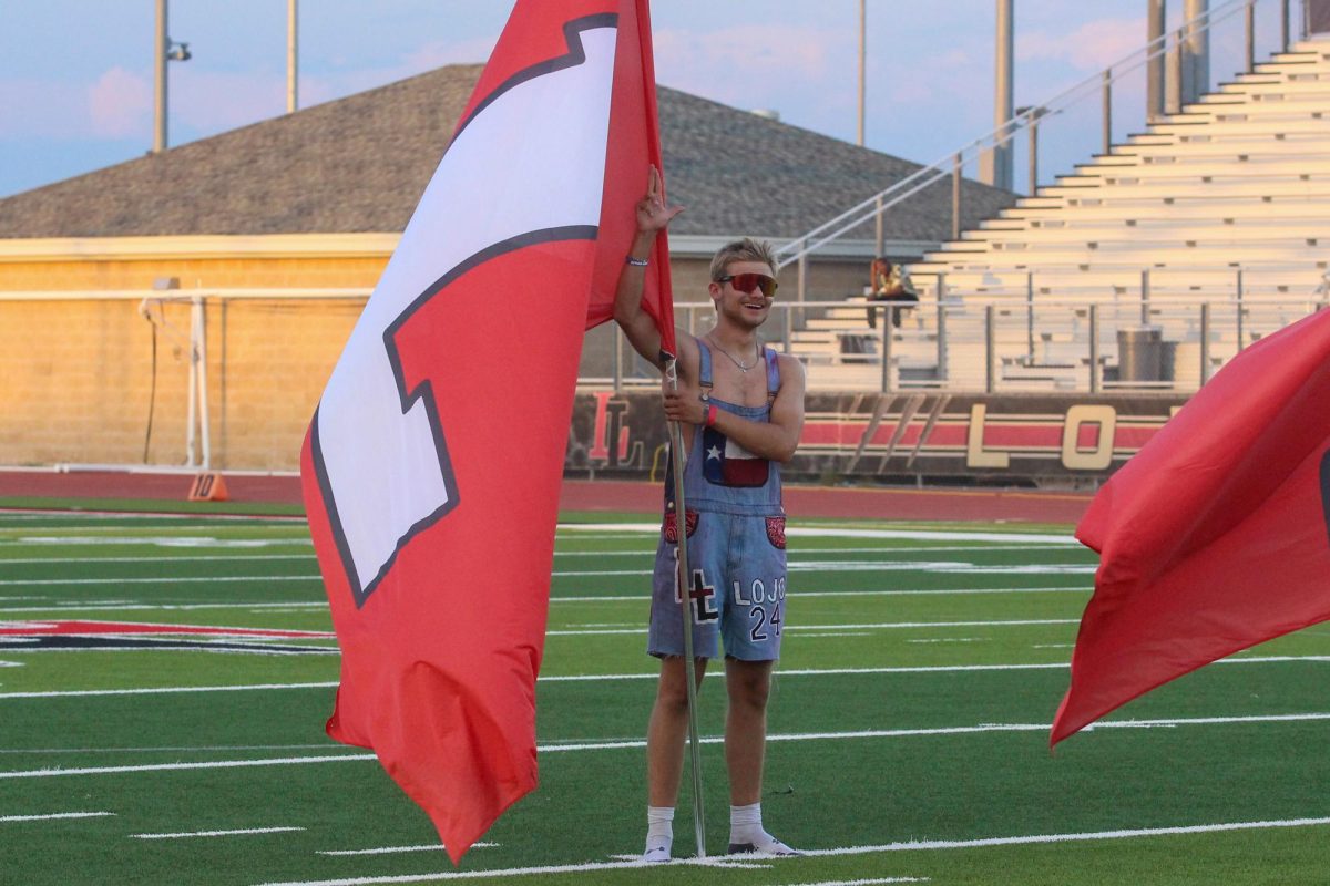 Senior Zane Evans holds a flag as he does the schools Alma Mater. Evans is the leader of the drumeline. 