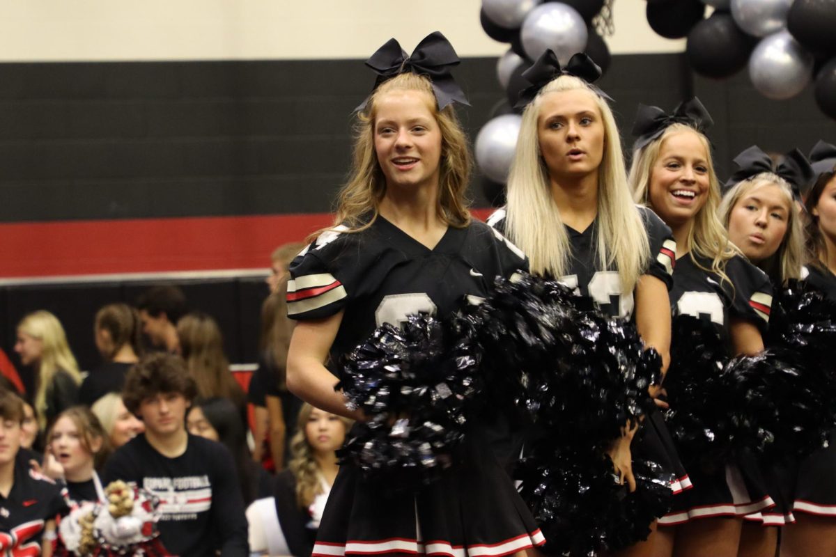 Junior cheerleader Rachel Dobbs cheers for the Cross Country team after they walk into the gym. Dobbs is a runner on the team.
