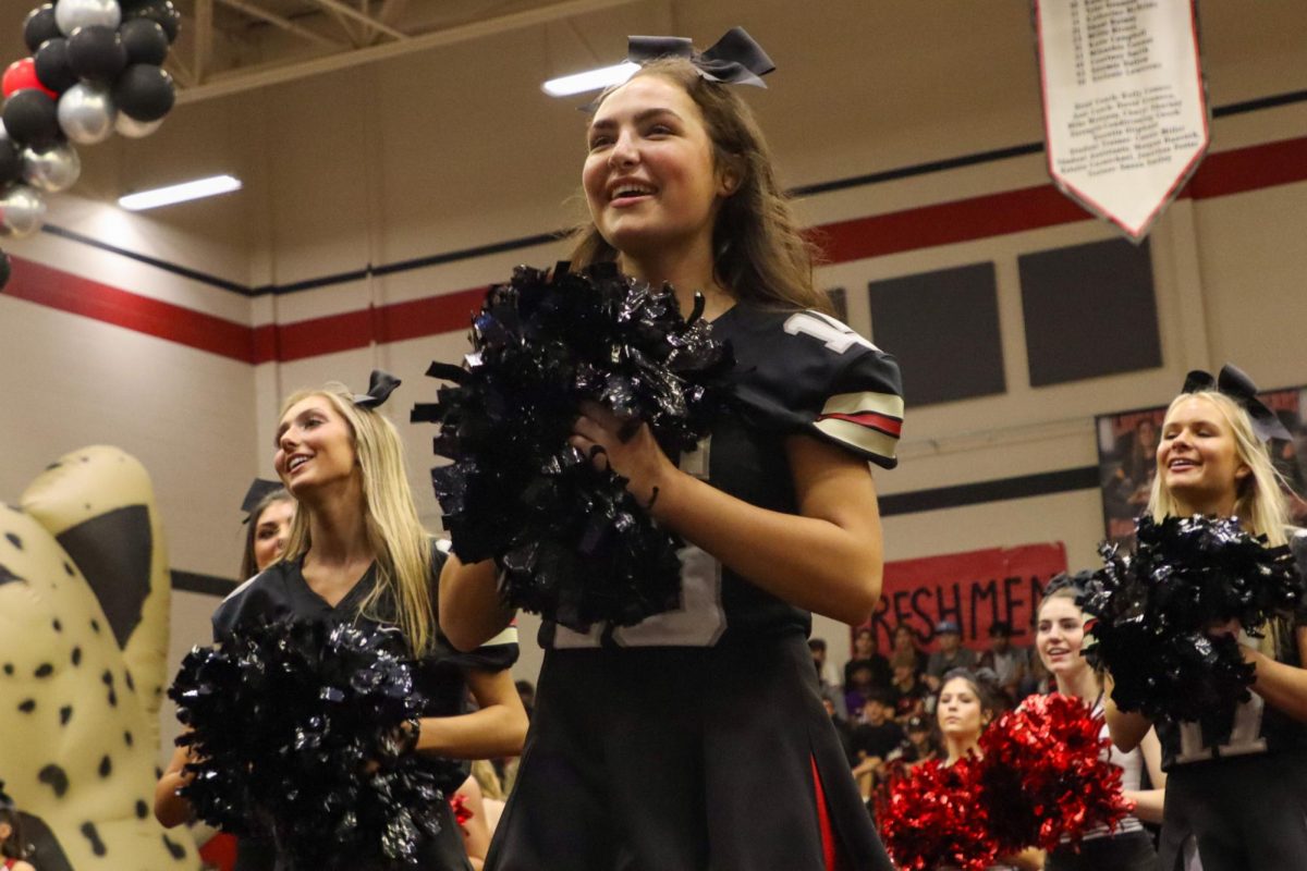 Senior Brianna Murphy cheers as the students enter the gym. The cheerleaders wear football jerseys for the homecoming game.