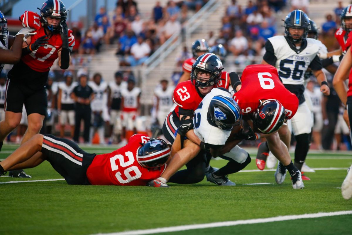 A group of defenders tackles a North Crowley player. The group was made of senior no. 9 Mason Dragoo, junior no.29 Gavin Prince, and junior no.23 Owen Magee.
