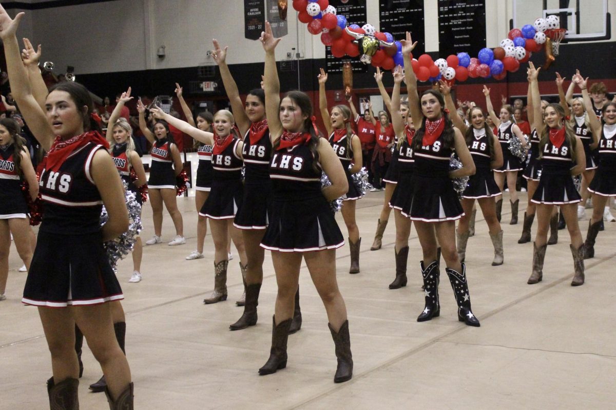 The cheerleaders stand hold up a double L as they do the alma mater. The theme of the pep rally was western.
